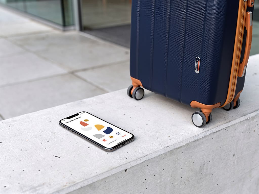 Persona che compila la prenotazione del deposito bagagli sullo smartphone accanto a una valigia